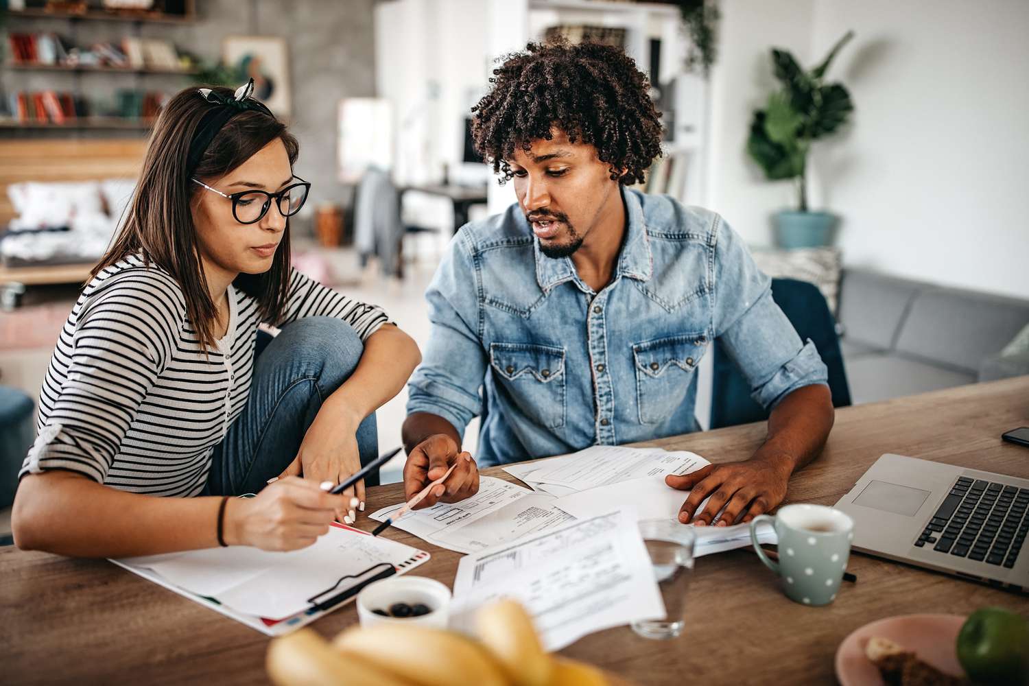 a man and woman sitting at a table looking at financial papers for money management